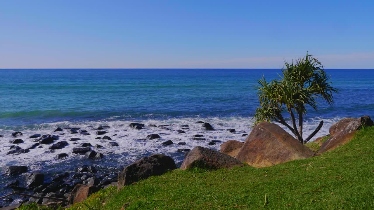 mar azul tranquilo con olas salpicadas en la costa rocosa - playa de burleigh heads - costa dorada, queensland, australia