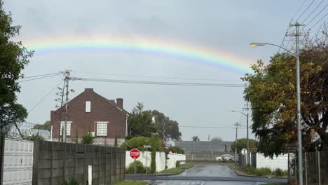 a rainbow over a suburb of cape town, on a rainy day on a cold winter’s day.