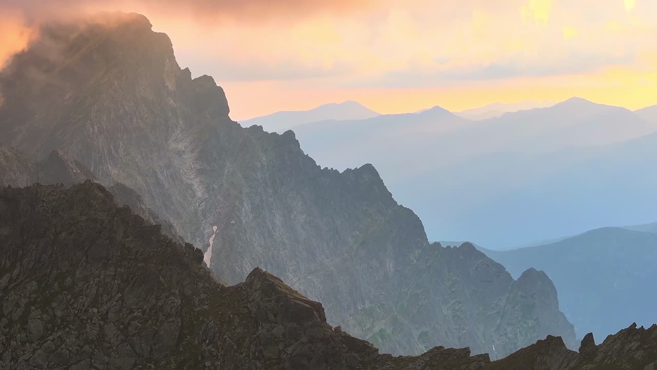 vasto paesaggio di montagna dinamico lento stabile drone girato al tramonto in ambiente alpino con nuvole arancione e rosa