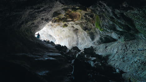 person exploring a dark cave with a bright exit