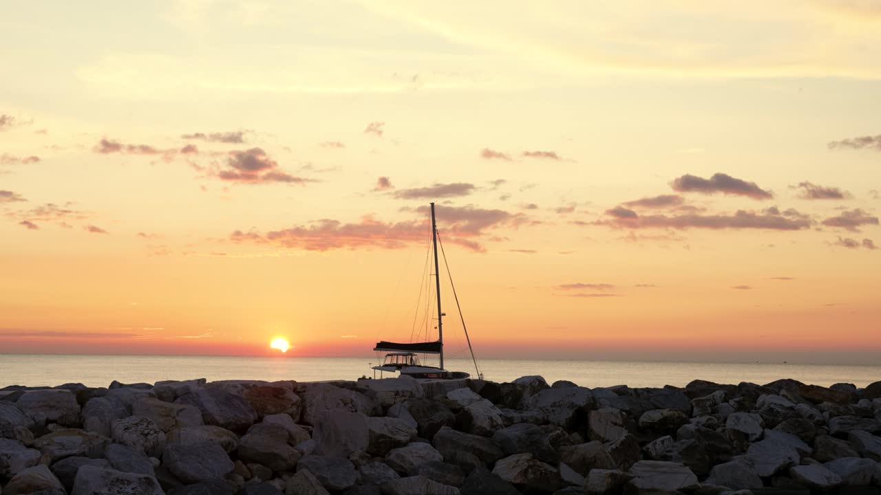 Sailboat at sunset in Italy with serene rocky foreground