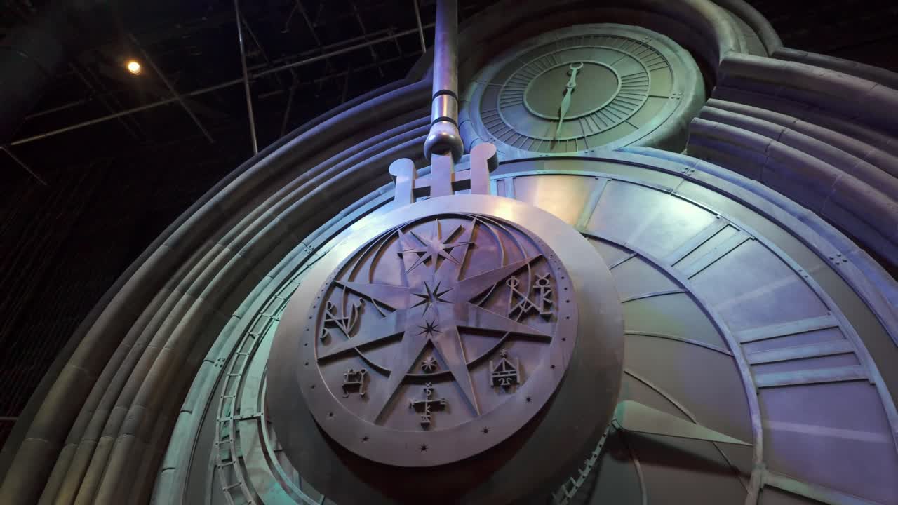 Giant, ornate pendulum swings on clock face. Dutch angle.