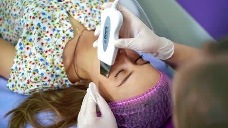 doctor with ultrasonic scraber. procedure of ultrasonic cleaning of face. patient in beauty clinic. healthcare, clinic, cosmetology. video from the top.