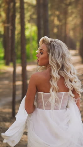 pretty woman bride with flying curly hair in elegant wedding dress runs looking back and holding chiffon skirt hem in pine forest slow motion