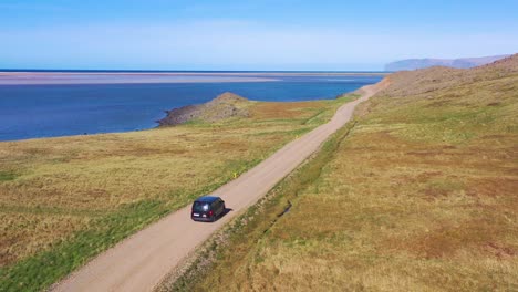 aerial over a black van traveling on a dirt road in iceland near raudisandur beach in the northwest fjords