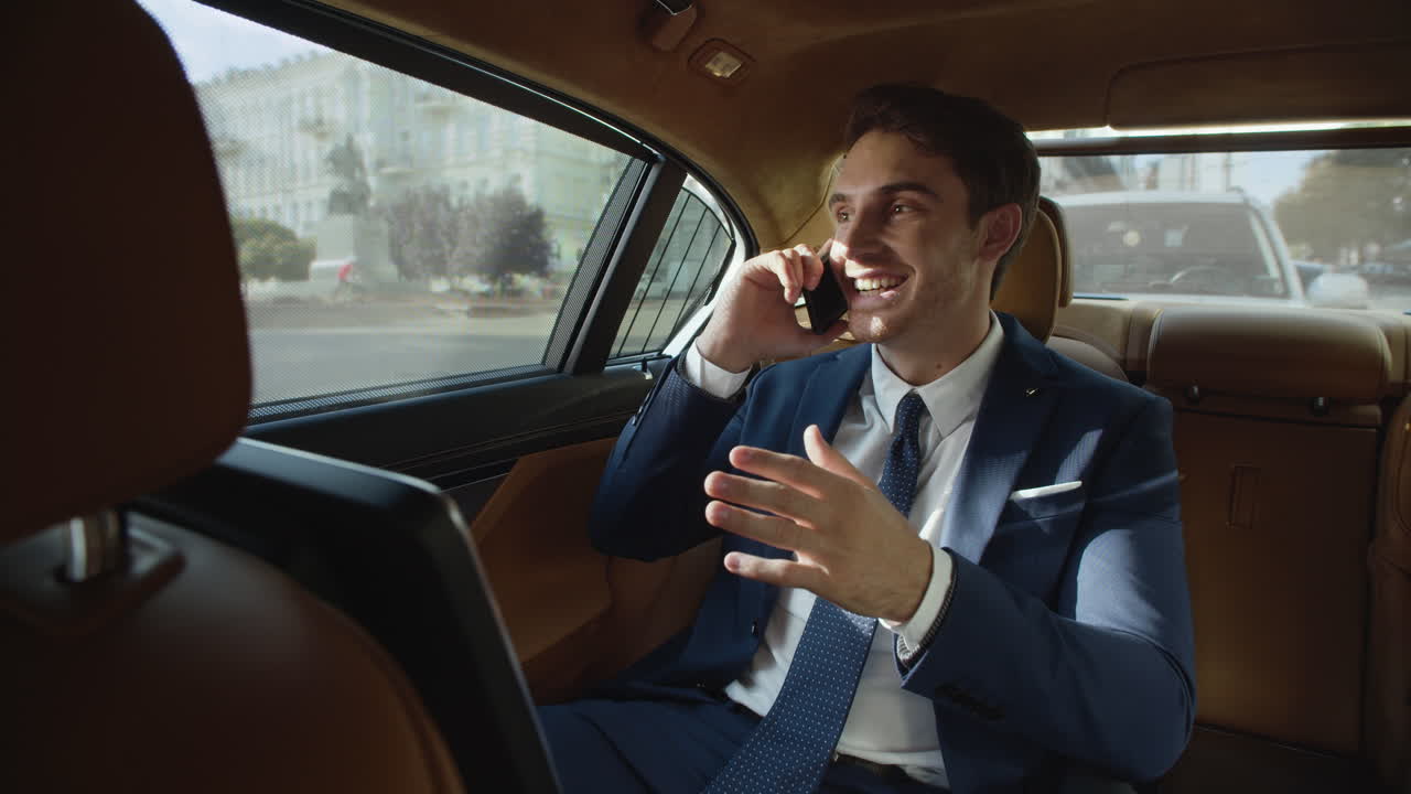 Uomo d'affari sorridente che parla al cellulare nell'abitacolo di un'auto aziendale