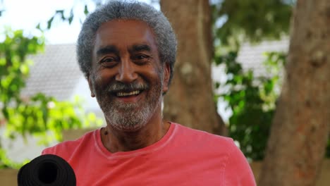 smiling senior man holding yoga mat in garden 4k