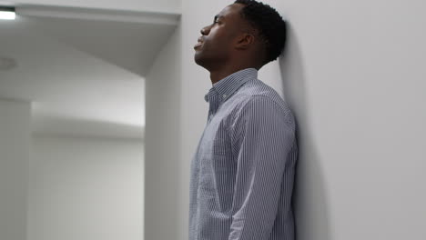 young businessman in office looking at message with bad news on mobile phone and leans against wall looking unhappy and depressed 3