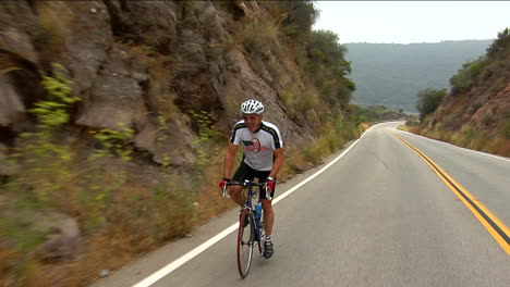 a bicyclist peddles along a highway in a mountainous area