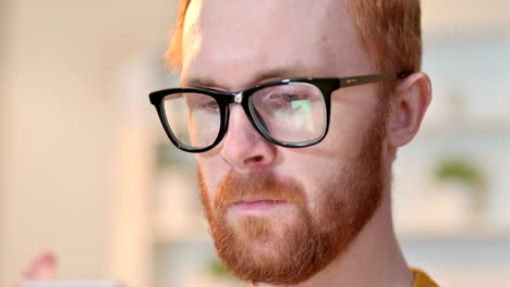 close up of face of redhead man using digital device