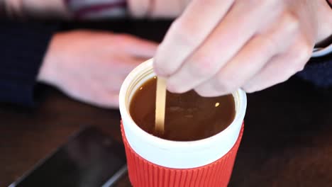 clip taken at coffee shop cafe of a caucasian women stirring and drinking from a refillable cup with hot coffee or tea in it