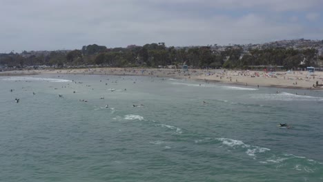 a beautiful aerial drone shot, tracking and circulating surfers waiting for waves close to the beach, dana point - orange county - california