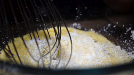 mixing dry cornmeal and cornstarch ingredients with whisk, slow motion close up