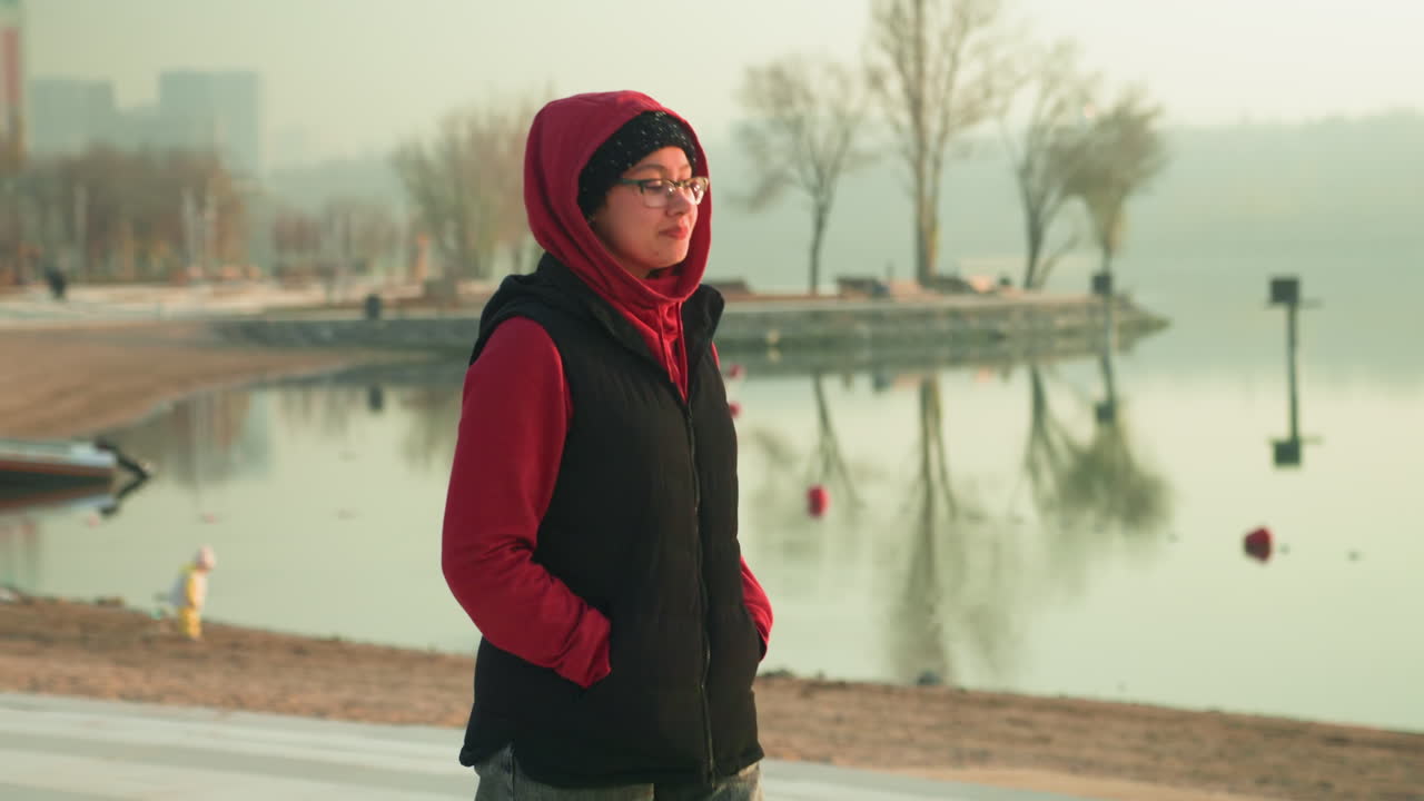 Ritratto casuale sul lungomare. Donna rilassata sul lungomare della città che sorride. Ritratto femminile casuale vicino al fiume durante le ore mattutine. Donna con espressione allegra in piedi sulla riva urbana all'alba.