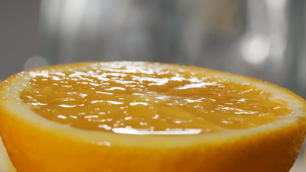 toma macro de jugo de naranja cayendo sobre una rodaja de naranja fresca, cámara súper lenta
