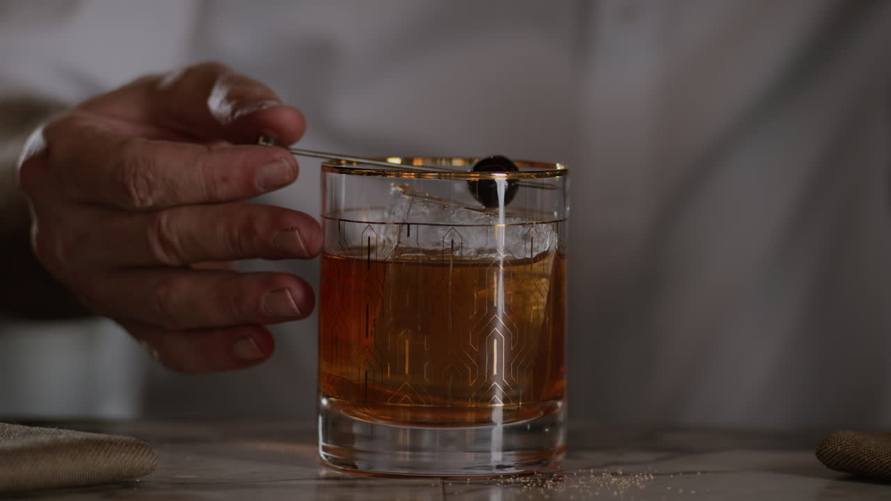 바텐더는 마라시노 체리 (maraschino cherry) 와 함께 구식 술을 장식합니다.