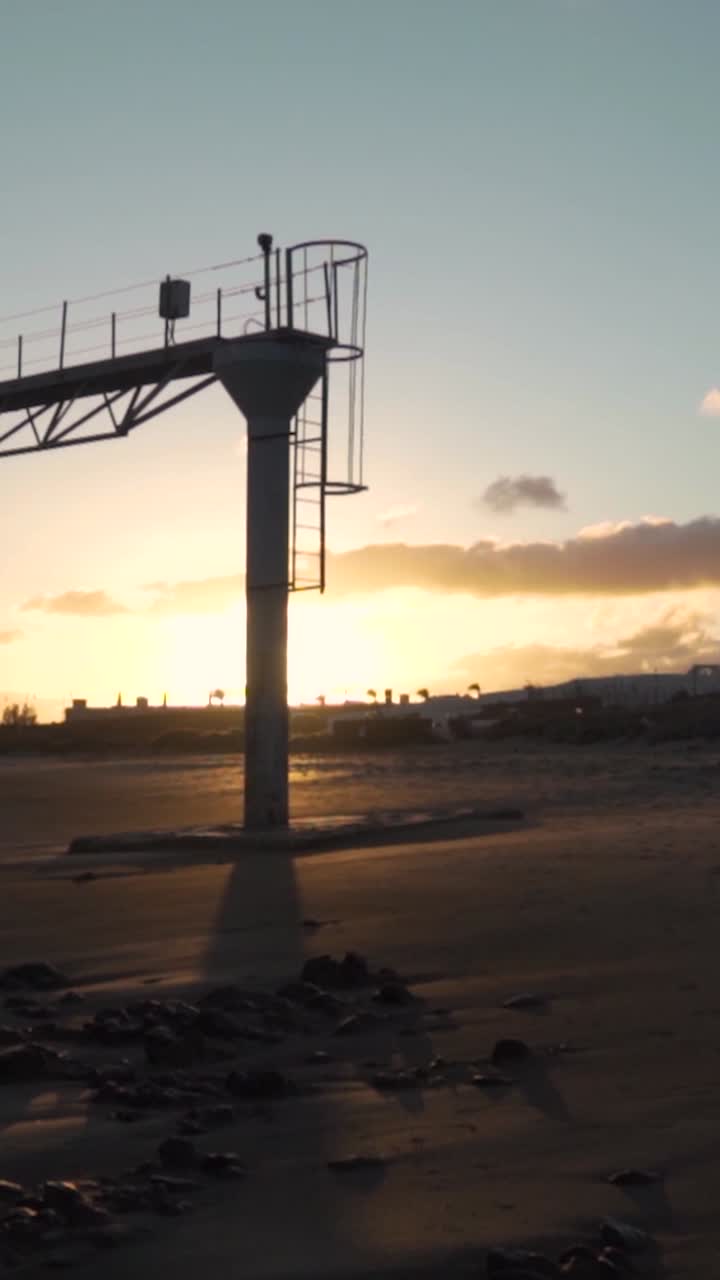 puesta de sol sobre una playa desierta con una torre de observación