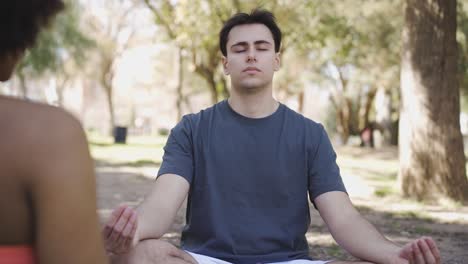 calm man meditating in lotus pose in park