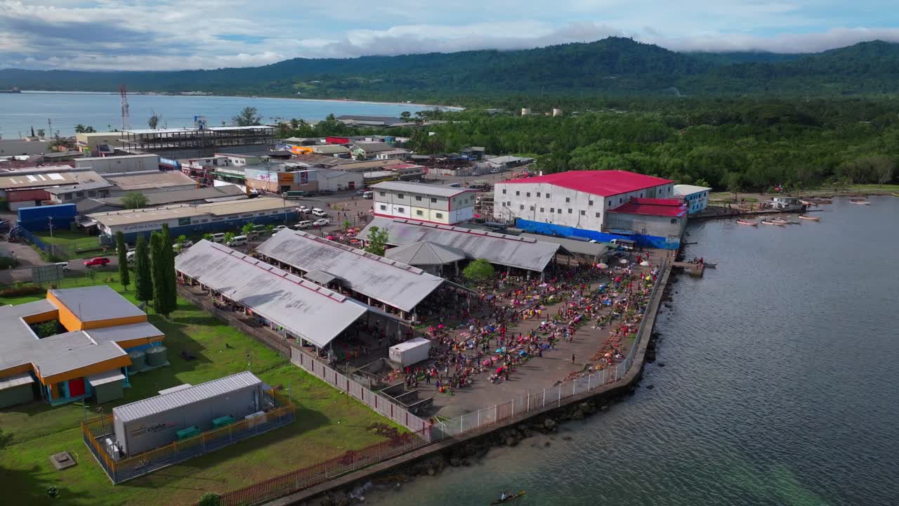 Wewak Sundaun fish Market Wewak Hill buildings cars traffic people Boram road Papua New Guinea aerial drone downtown coastal town city center Dogreto Bay sunny morning blue sky backwards motion