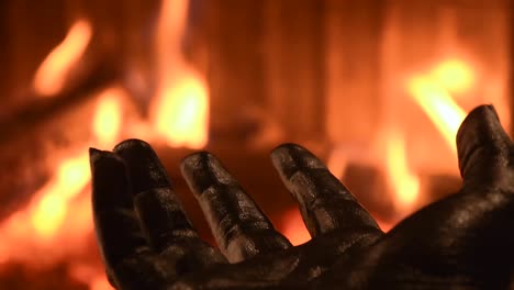 young-female-hand-painted-with-black-color-moving-smoothly-with-a-blurred-fireplace-in-the-background