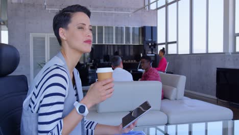 hermosa mujer de negocios caucásica usando una tableta digital mientras bebe café en una oficina moderna 4k