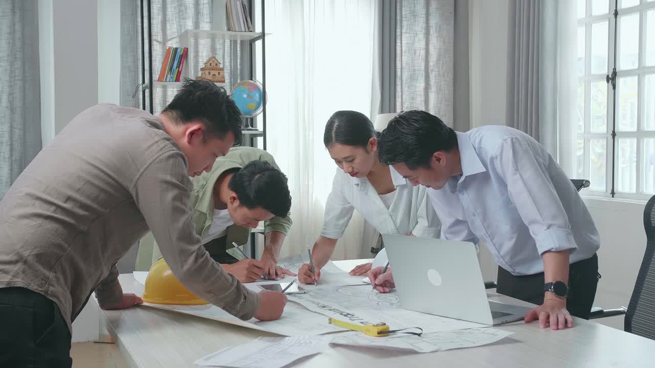 Group Of Asian Engineers Drawing Building Construction At The Office