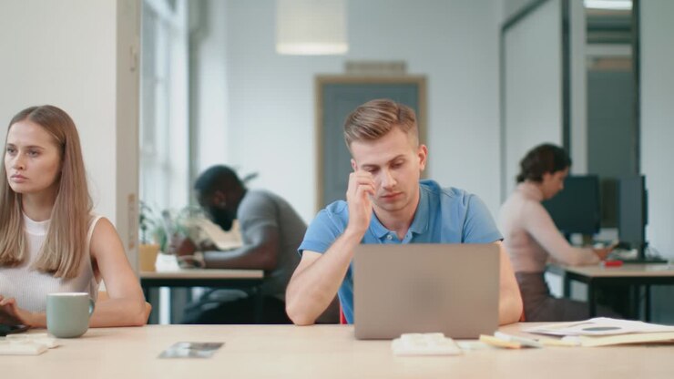 Müder Mann schläft mit Notizbuch im Coworking Büro. Erschöpfter Geschäftsmann.