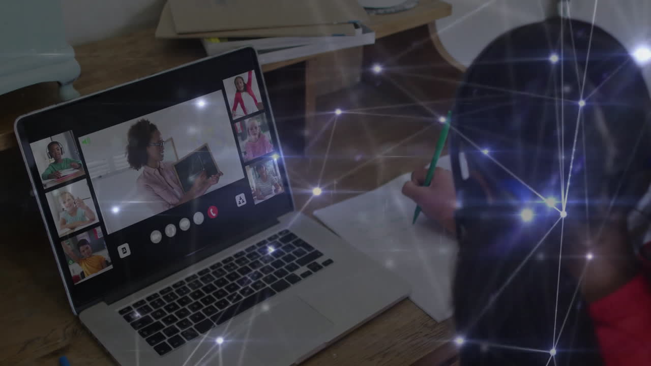 In school, person writing notes while attending virtual meeting on laptop