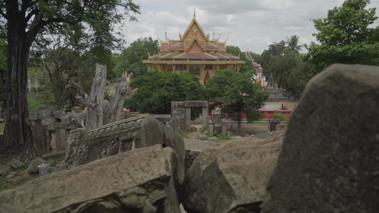 Teenagers visiting-leaving Ek Phrom temple near Battambang in Cambodia on a cloudy day.  Ek Phrom pagoda in the background.