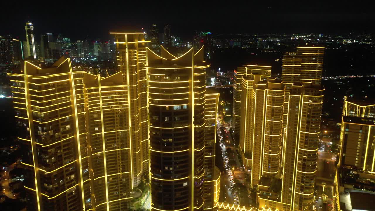 Aerial footage of Rockwell Center skyscrapers in Makati, Metro Manila, glowing with lights at night and surrounded by the vibrant energy of the city skyline.