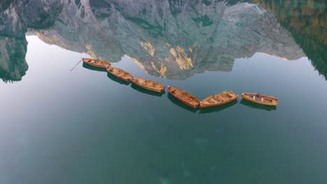 escena cinematográfica, botes de remos de madera, lago braies, increíble reflejo de montaña en el fondo