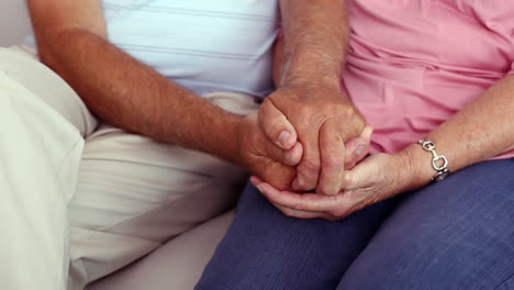 Senior-couple-holding-hands-on-the-couch