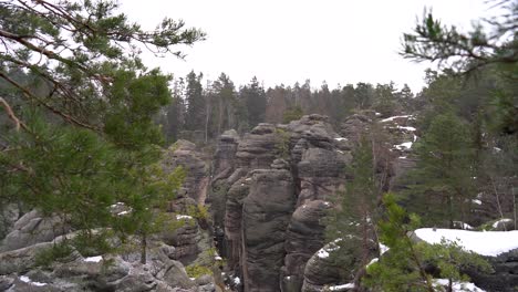 outlook on a sandstone rock formation through branches in prachov rocks, bohemian paradise, in winter, dolly in