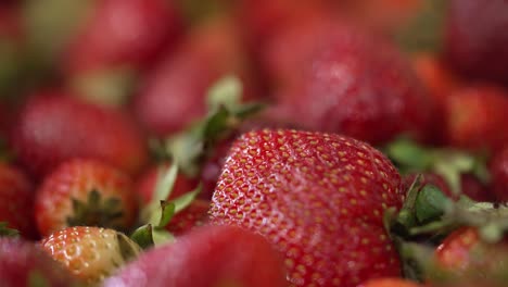 close up view of delicious ripe strawberries with their leaves on being processed at a factory