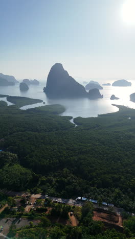 tall limestone karsts emerge from flat jungle in phuket, thailand with distant haze, vertical aerial establishing