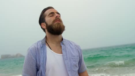 vista frontal de un hombre caucásico de pie con los ojos cerrados en la playa 4k