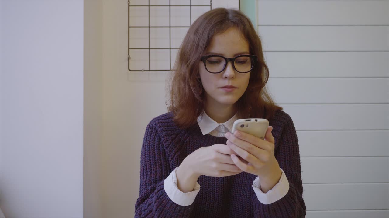 una adolescente usando un teléfono inteligente en un café