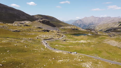 A-drone-rises-in-breathtaking-mountain-scenery-and-shows-driving-cars-arriving-at-a-mountain-lake