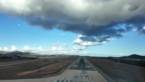 real time landing at ibiza’s airport as seen by the pilots from the cockpit of a jet. blue sky with a grey darkening cloud. 4k 60fps