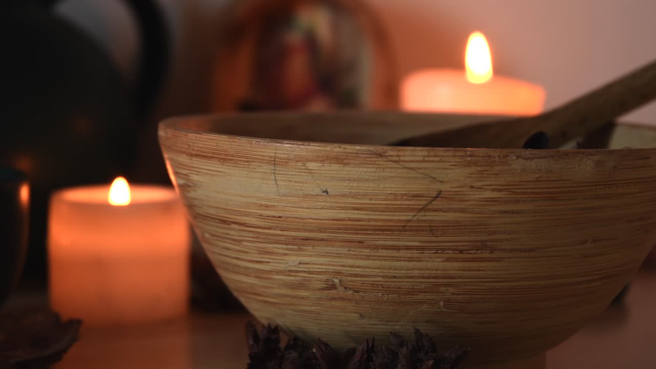 relajante plano de detalle de fondo de velas con llamas parpadeantes, una tetera, una taza con vapor saliendo, hierbas y un cuenco de madera