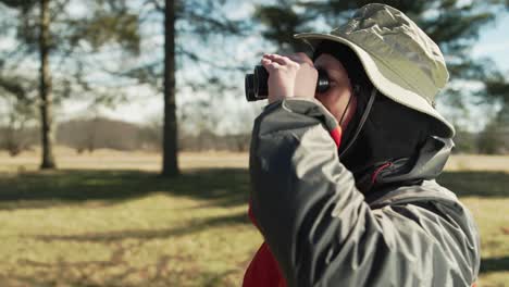 man out in nature taking photographs and looking with his binoculars