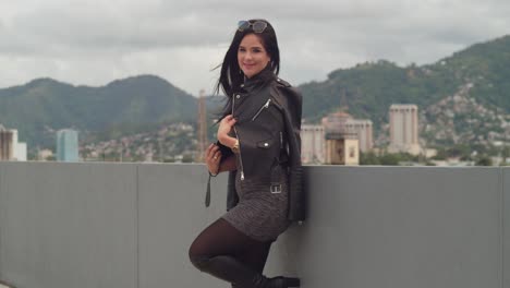 a woman is having fun on a rooftop with the urban landscape of port of spain, trinidad, behind her