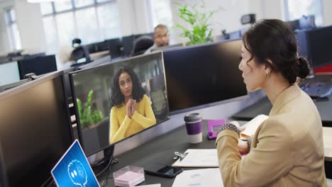 Diverse-business-people-having-video-call-and-using-laptop-with-digital-chat-on-screen-in-office