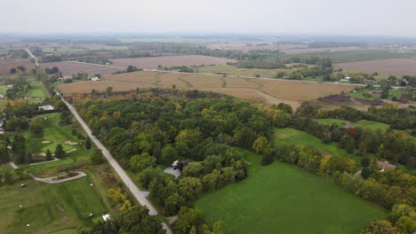 vista aérea a gran altitud del paisaje natural del campo en la temporada de otoño, caminos rurales al lado del campo de golf del parque verde y vastas tierras agrícolas alrededor, horizonte en el horizonte