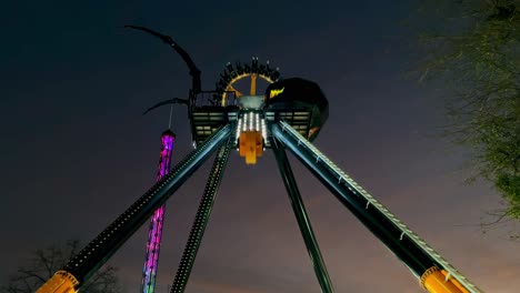 static visual of a spider-shaped structure, amusement park game with round pendulum shape at night.