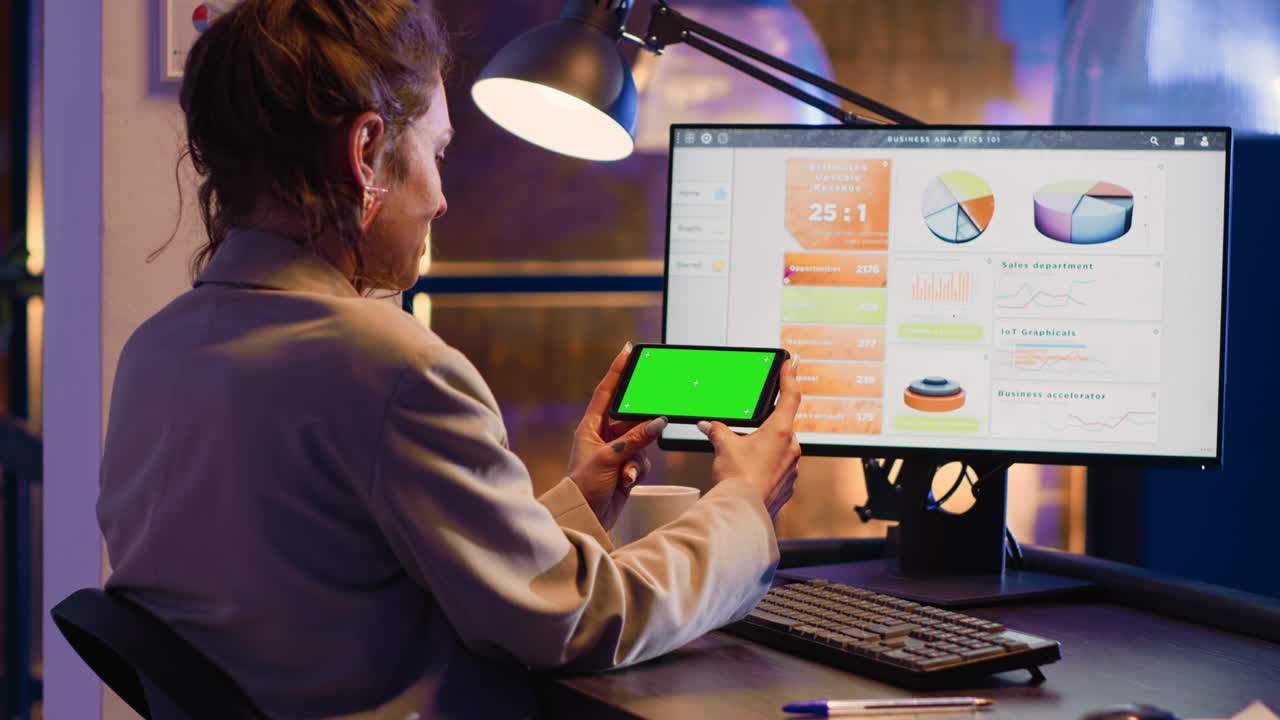 Woman analyzing business data on computer with green screen tablet