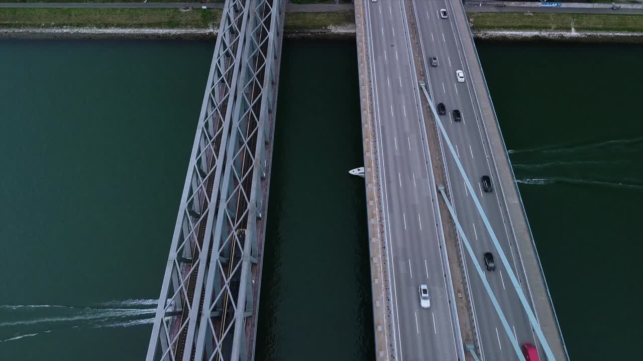 High altitude drone footage of german bridge over the Rhine River with lots of cars and two speed boats passing under the calm water ways