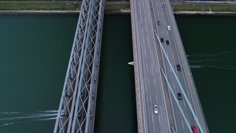 high altitude drone footage of german bridge over the rhine river with lots of cars and two speed boats passing under the calm water ways