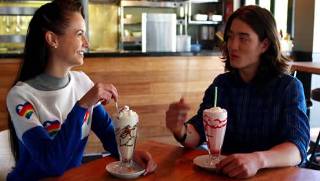 happy couple interacting with each other while having milkshake