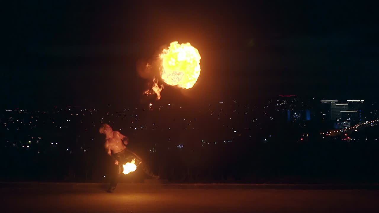 Young blond male does tricks with fire breaths fire in midnight Male breaths out large stream of fire